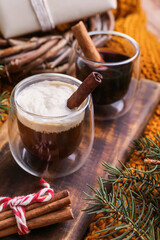 Glasses of tasty coffee with cinnamon and fir branches on table