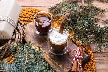 Glasses of tasty coffee with cinnamon and fir branches on wooden background