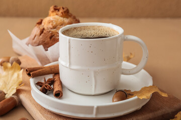 Cup of coffee with acorns, autumn leaves and cupcake on color wooden table, closeup