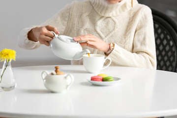 Young woman drinking tasty tea at table in cafe