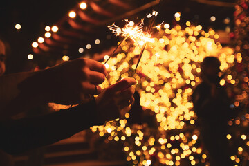 Fototapeta na wymiar Two hands with sparklers on a Christmas or New Year's eve background