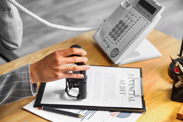 Female notary public attaching seal to document in office