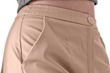 A close-up female figure in beige trousers sideways. Side trouser pocket. Concept: ready-made clothes, classic style, atelier, cutting and sewing courses, custom tailoring, self-sewing, clothing brand