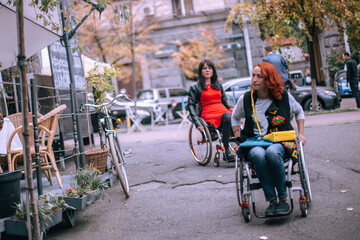 Girls in wheelchairs choose cafe accessible to people with special needs. Freedom of movement of persons with special needs