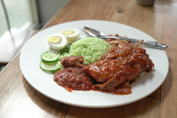 Nasi Lemak coconut rice with spicy fried chicken, boiled egg, curry, peanuts, anchovies and cucumbers. Ready to eat.