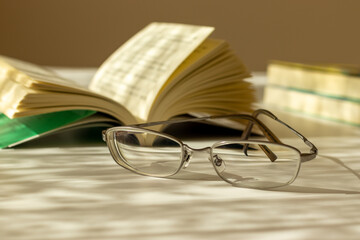 夕方の机の上に置かれたメガネと本