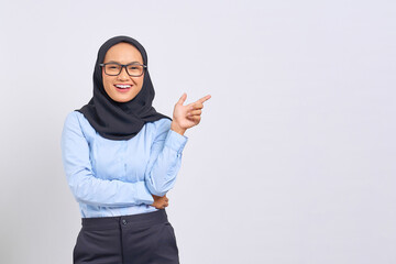 Portrait of smiling young Asian woman pointing finger at copy space isolated on white background