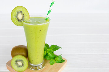 Kiwi yogurt fruit juice smoothie and green kiwi juice drink healthy, delicious taste in a glass for weight loss on a white wooden background.