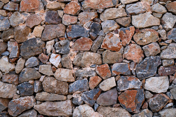 Textured background of masonry wall made of natural multicolored stones.