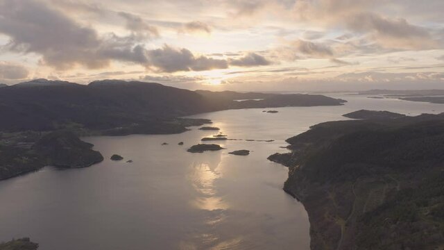 Golden clouds due to fire sunset over fiord; high altitude drone view