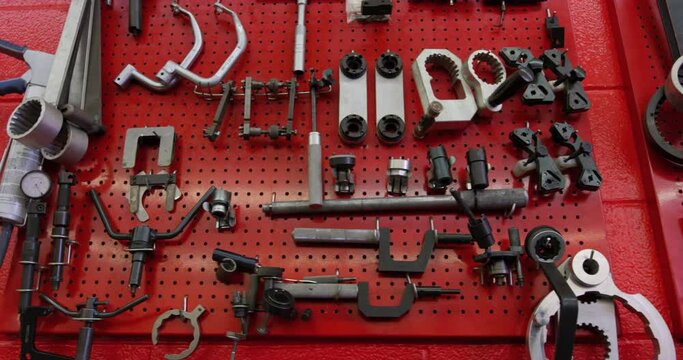 Set Of Mechanical Tools Organized On Red Pegboard On The Garage Wall. close up, slider shot