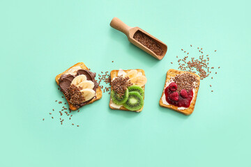 Tasty sandwiches with fruits and flax seeds on color background