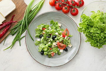 Plate with healthy Greek salad on light background