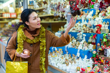 Positive female in tinsel on Christmas fair decoration on holiday