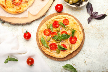 Board with tasty mini pizza on light background