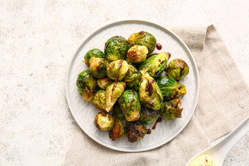 Plate with delicious roasted Brussels cabbage and sauce on light background
