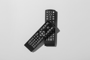 Black TV remote controllers on grey background