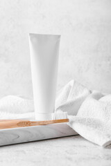 Marble tray with wooden toothbrush, paste and towel on light background