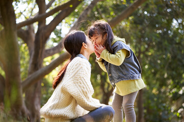 young asian mother enjoying a good time with daughter outdoors in city park