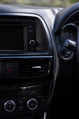 Buttons for audio, phone and sound volume on the dash board of a Japanese SUV car. Seeing an air grill for a ventilation.
