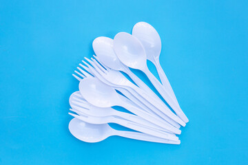 Plastic fork and spoon on blue background.
