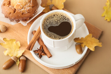 Cup of coffee with acorns, autumn leaves and cupcake on color wooden background