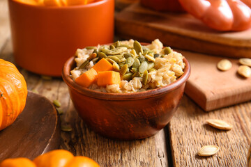 Bowl of tasty oatmeal with pumpkin on wooden background