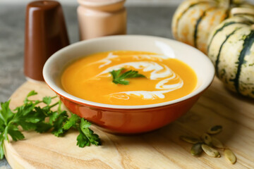 Bowl with delicious pumpkin cream soup and seeds on table, closeup
