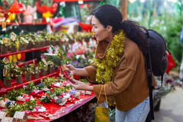 Portrait of smiling asian female purchasing christmas bouquet at fair in the evening