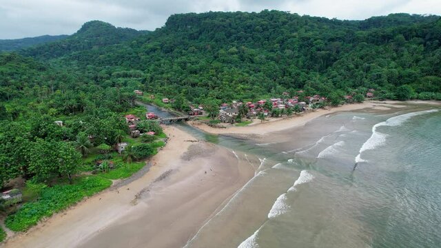 Aerial view around the Vila Malanza town and beach, in cloudy Sao Tome - Circling, drone shot