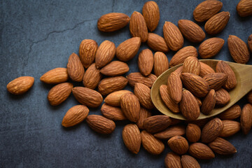 Almonds on wooden spoon and dark background top view on the table, Close up roasted almond nuts natural protein food and for snack