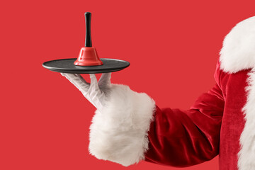 Santa hand with Christmas bell on red background