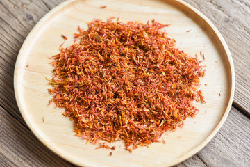 Dried safflower for herbal tea on tray wooden background, dry safflower petals, Saffron substitute - obrazy, fototapety, plakaty