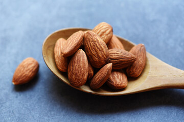 Almonds on wooden spoon and dark background top view on the table, Close up roasted almond nuts natural protein food and for snack