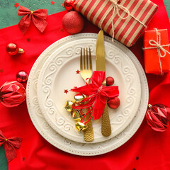 Beautiful Christmas table setting with decor and gift boxes on green background