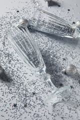 Champagne glasses with confetti and Christmas balls isolated on white background, closeup