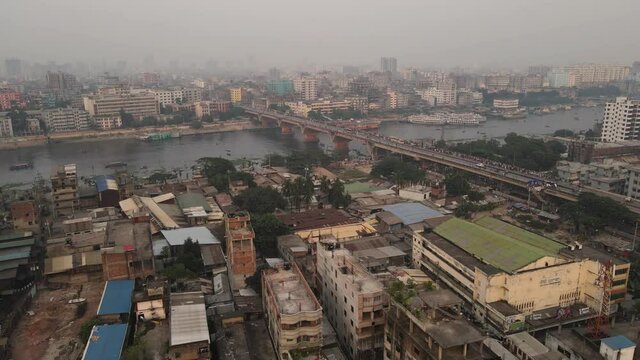 Low aerial pull out over the slums and poverty stricken areas of Old Dhaka near the Burigana River in Bangladesh