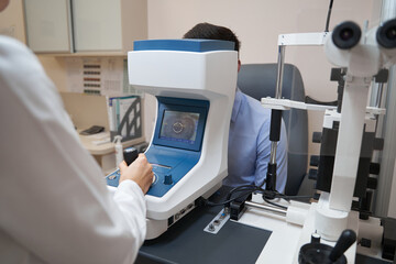 Eye physician checking man sight with autorefractor