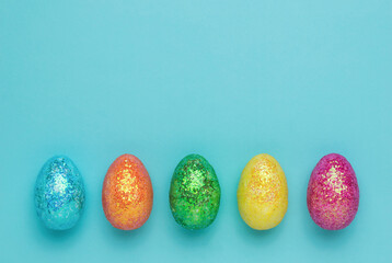 Five colorful Easter eggs on a blue background. Flat lay.