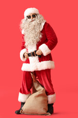 Santa Claus in sunglasses with sack bag on red background