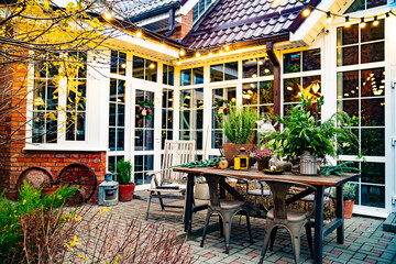 in evening. exterior of white house with large windows and garlands in courtyard