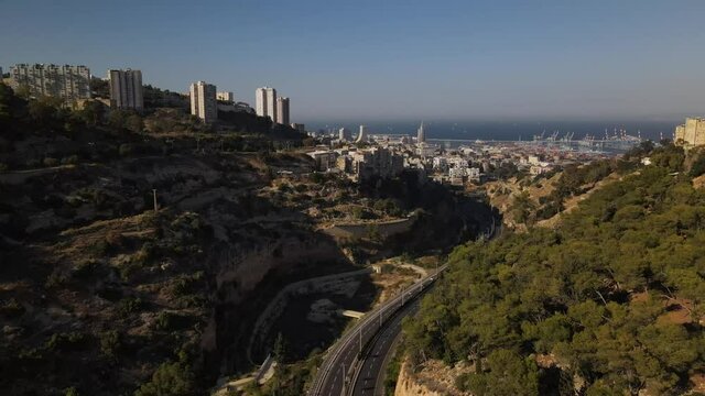 View over a winding road between the hills with the port city of Haifa in the early evening, horziont with the sea and boats, Israel