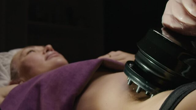 Young caucasian woman receiving anti-fat anti-cellulite professional vibration massage and relax in spa salon. Slow motion 120fps