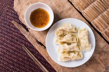 Steamed wonton dumpling stuffed with minced pork on plate eating with sesame oil sauce, Asian food, Table top view
