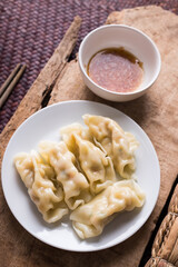 Steamed wonton dumpling stuffed with minced pork on plate eating with sesame oil sauce, Asian food, Table top view