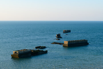 The floating concrete elements of the American artificial harbor in Europe, France, Normandy, Arromanches les Bains, in summer, on a sunny day.