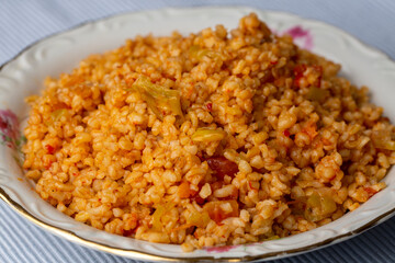 Traditional turkish bulgur pilaf with tomato sause in plate (Turkish name; meyhane pilavi)