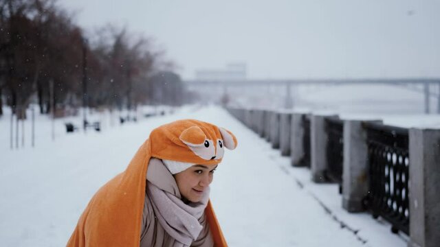 Funny woman in a funny costume of a red squirrel on the background of a winter park. The woman is acting funny, pretending to be a squirrel.
