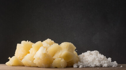 boiled cassava or manihot with coconut scrapes, also known as manioc, yuca or brazillian arrowroot with grated coconut, vegetarian dish on a wooden surface