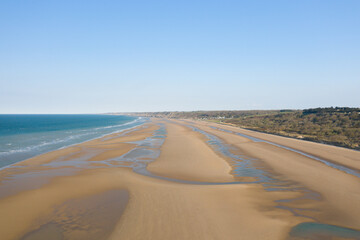 Fototapeta na wymiar The immense fine sand beach of Omaha beach in Europe, in France, in Normandy, towards Arromanches, in Colleville, in spring, on a sunny day.